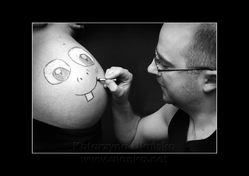 Fotografia ciążowa, mężczyzna rysujący na brzuchu żony w ciąży