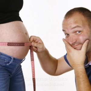 Fotografia ciążowa, mężczyzna mierzący obwód brzucha żony w ciąży