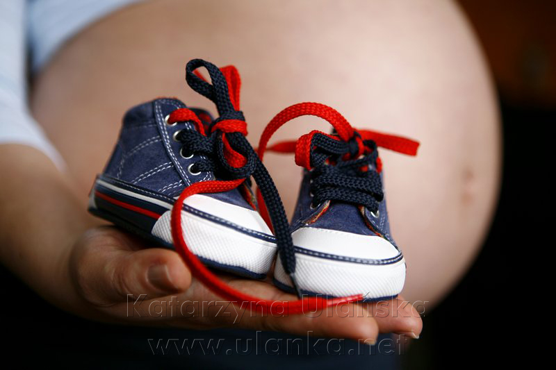 Fotografia ciążowa, buciki dziecięce na tle brzuszka