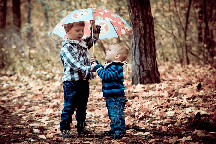 Dwaj chłopcy pod parasolką wśród liści