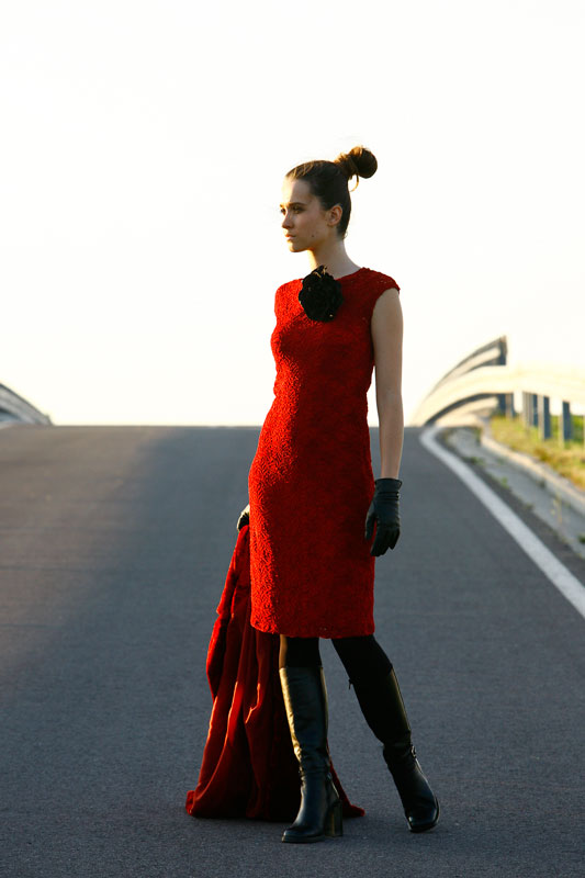 Fotografia mody, modelka w czerwonej sukience i skórzanych butach stojąca na ulicy