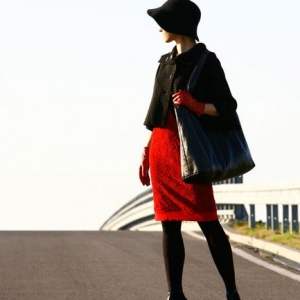 Fotografia mody, modelka na ulicy w czerwonej sukience i czarnym żakiecie i kapeluszu