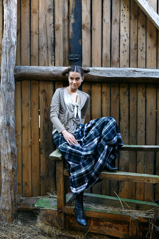 Moda, modelka w sukience w kratę siedząca w stodole