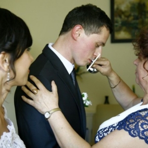Fotografia ślubna - pan młody całujący krzyż