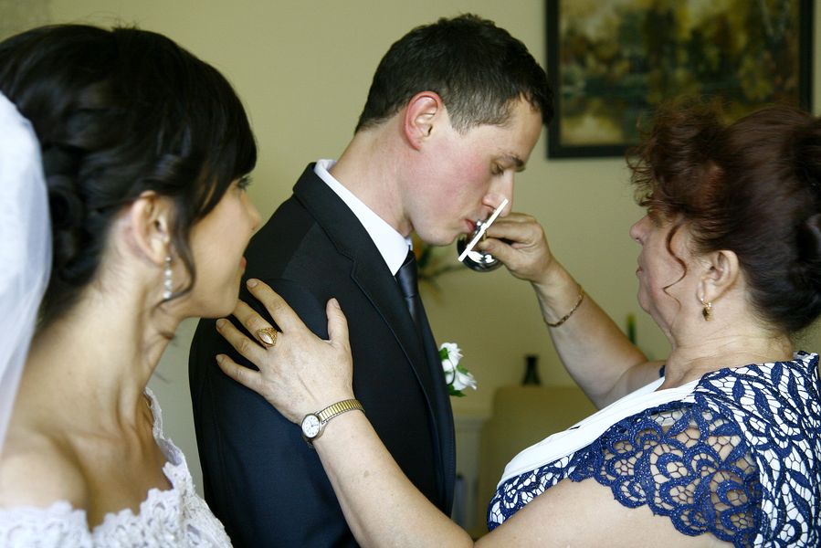 Fotografia ślubna - pan młody całujący krzyż