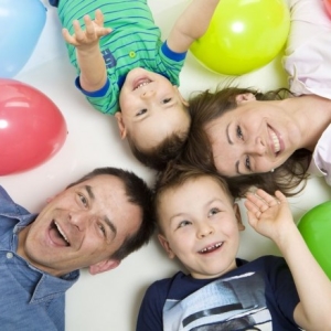 Fotografia rodzinna, zdjęcie rodziny leżącej na ziemi wśród balonów, ujęcie z góry