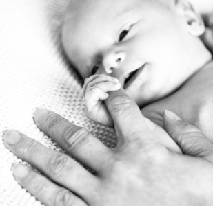 Noworodek trzymający palec rodzica
