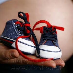 Fotografia ciążowa, buciki dziecięce na tle brzuszka