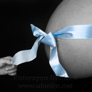 Fotografia ciążowa, brzuch kobiety w ciąży owinięty wstążką