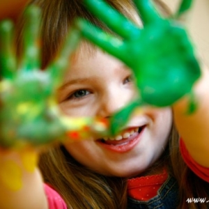 Fotografia dziecięca - uśmiechnięta dziewczynka z pomalowanymi rękoma na zielono