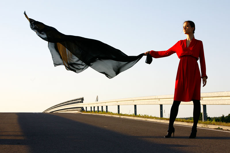 Fotografia mody, modelka w czerwonej sukni stojąca na jezdni