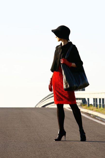 Fotografia mody, modelka na ulicy w czerwonej sukience i czarnym żakiecie i kapeluszu