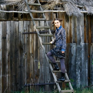 Modelka stojąca na drabinie przy stodole