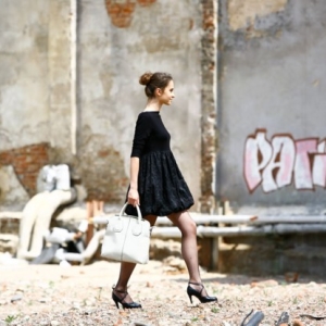Fotografia mody, idąca modelka w czarnej sukience na tle starego muru