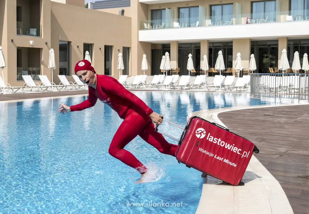 Zdjęcie reklamowe – postać w czerwonym kostiumie przy hotelowym basenie