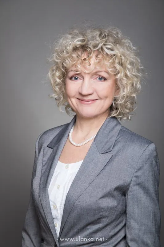 Portret biznesowy kobiety w szarej marynarce i perłach
